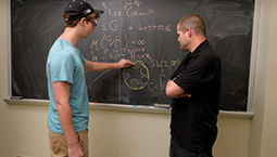 Student with tutor in front of blackboard.